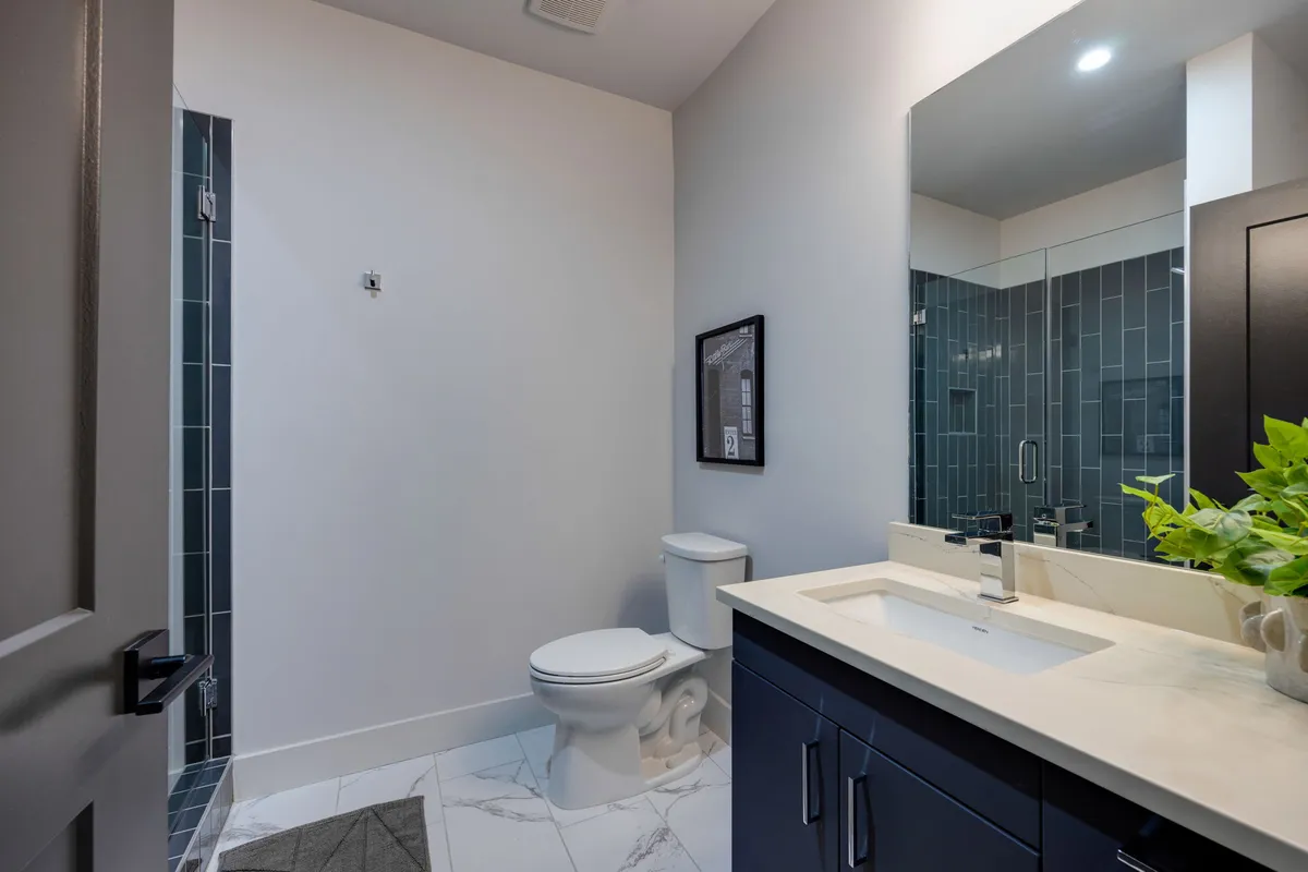 A modern bathroom with a spacious vanity, stylish sink, framed artwork, and a clear view of the shower area. The atmosphere is fresh, inviting, and optimized for daily routines.