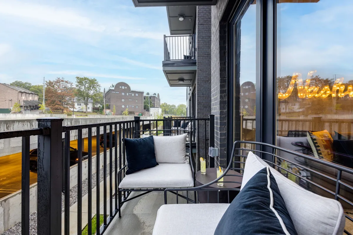 This image features comfortable balcony seating with a view of the city and a decorative sign, creating an inviting space for relaxing or socializing in the fresh air. The scene perfectly illustrates the private balcony experience described in the section.